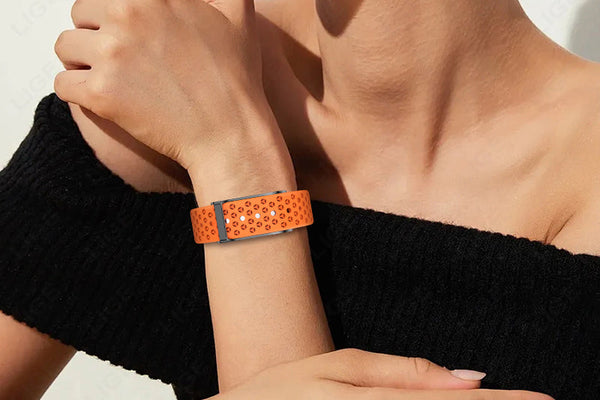 "A fashionable woman wearing a vibrant orange sports watch with a perforated strap, complementing her elegant black off-shoulder outfit."